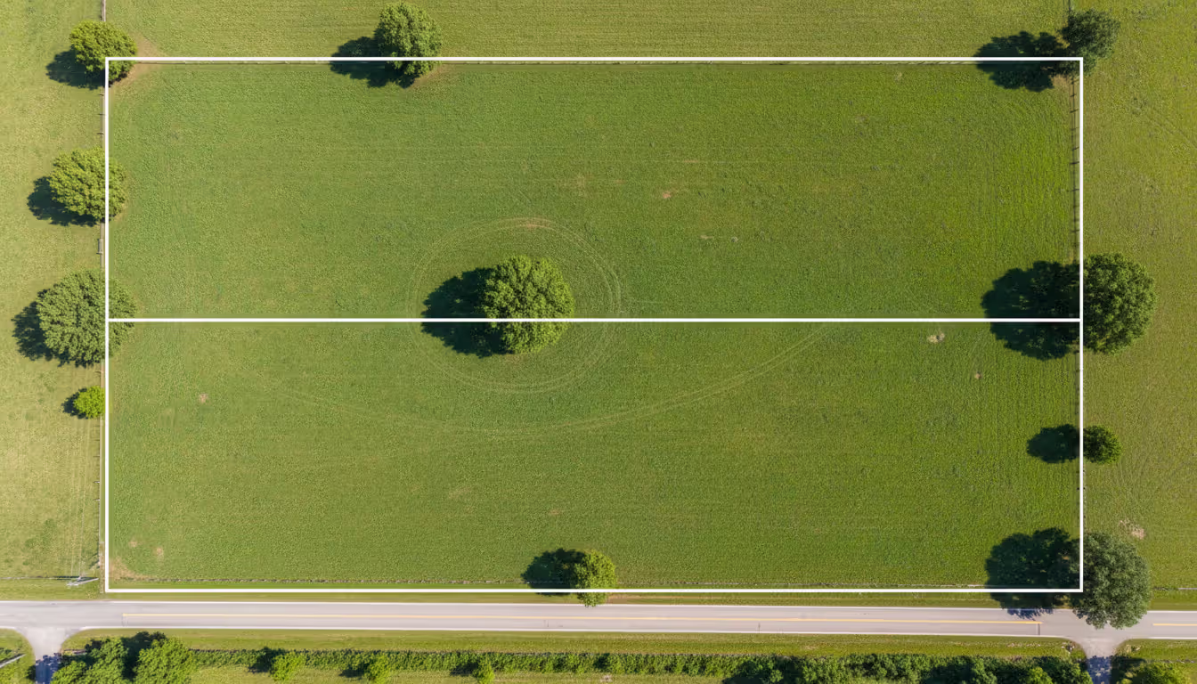 Aerial view of a large rectangular land parcel divided into two equal halves by a clear boundary line along a highway, illustrating partition in kind
